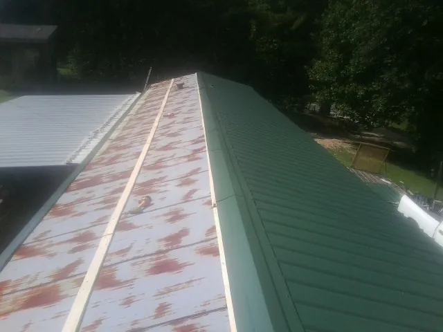 Old rusted panels beside newly installed green metal roofing — Wind Damage Roof Repair by Roofing Brothers in Carmel By The Sea