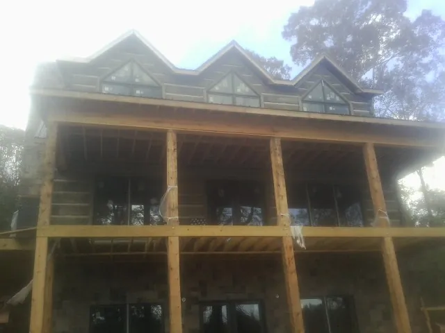 Dormers and porch framing on a large log home under construction — Roof Coating work by our crew in Carmel By The Sea