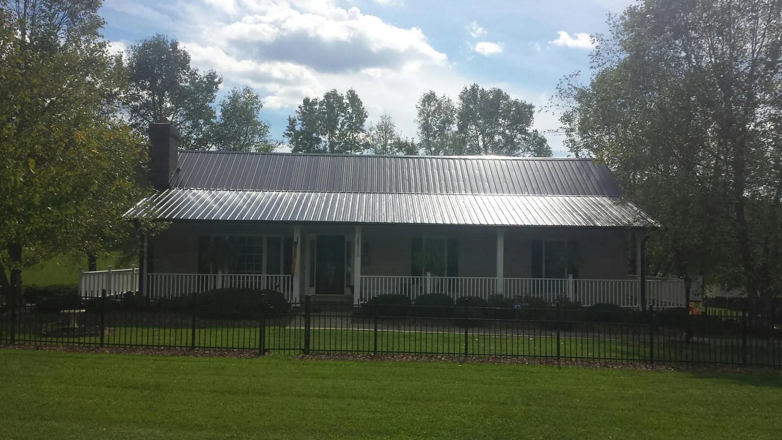 Gray metal roof on a brick ranch with a full width front porch — Gutter Guard Installation work by our crew in Carmel By The Sea
