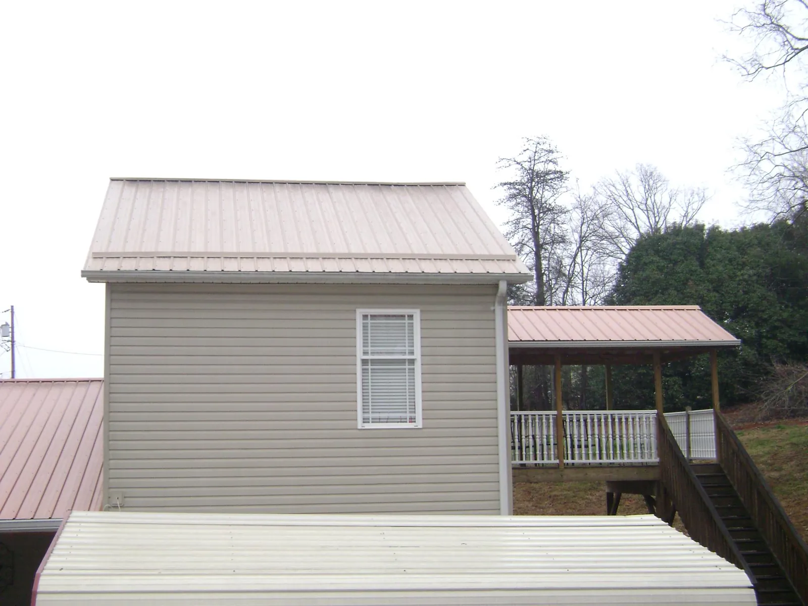 Tan metal roofs on a two story addition and attached porch, from a Roof Replacement job in Carmel By The Sea