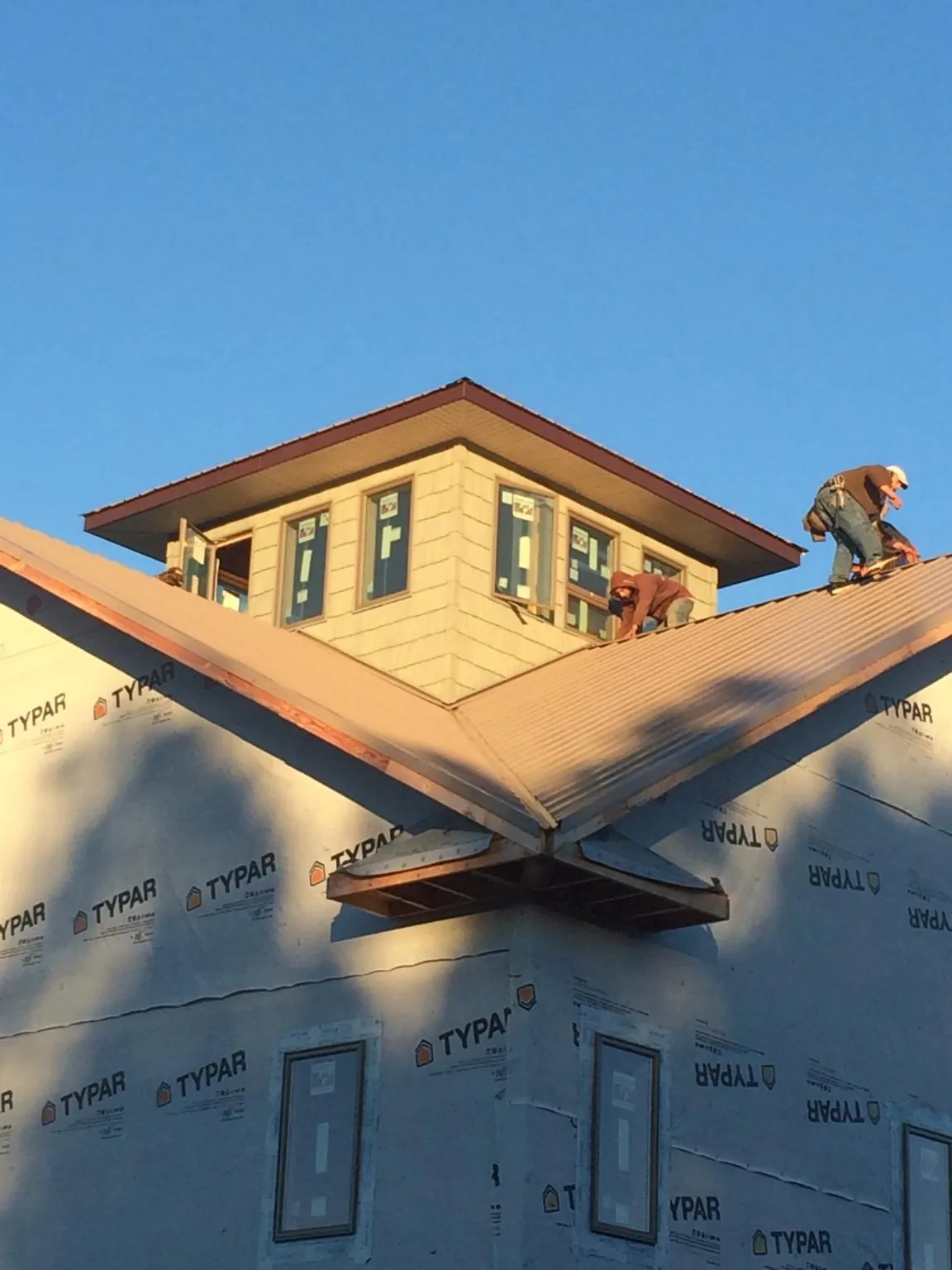 Roofers working around a rooftop cupola on a new metal roof at sunset — Roof Waterproofing in Carmel By The Sea by Roofing Brothers